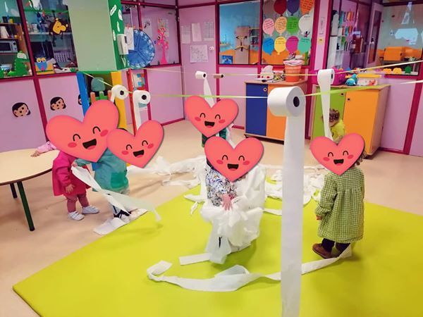 Un grupo de niños está jugando con papel higiénico en una habitación.
