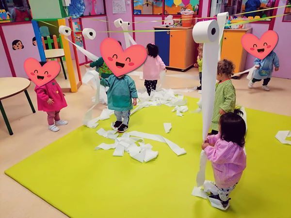 Un grupo de niños con corazones en sus caras están jugando con papel higiénico.