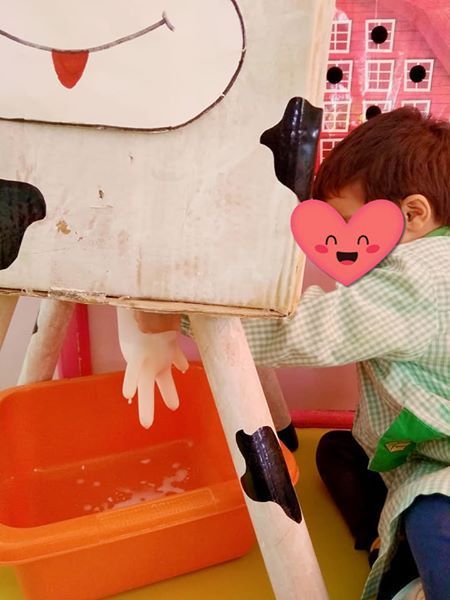 Un niño con un corazón en la cara está jugando con una vaca de juguete.
