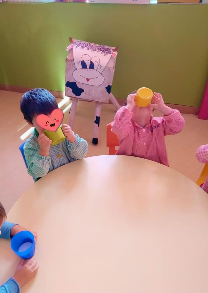 Un grupo de niños está sentado en una mesa bebiendo de tazas.