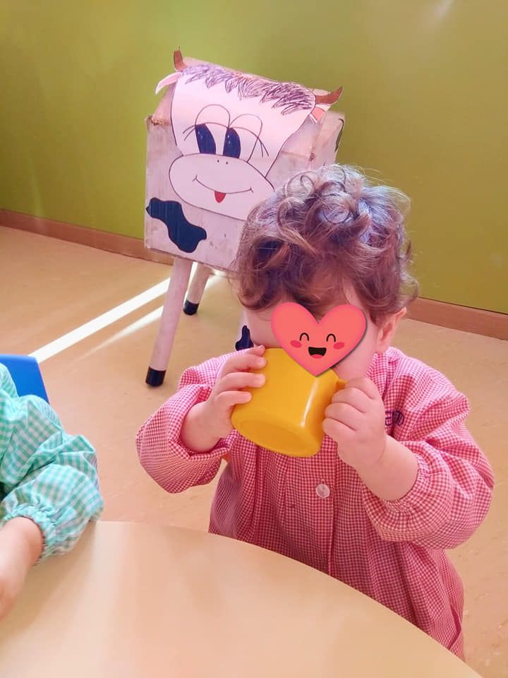 Una niña con un corazón en la cara está bebiendo de una taza amarilla.