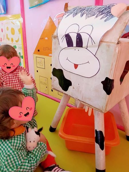 Una niña está jugando con una vaca hecha con una caja de cartón.