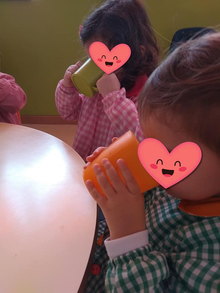 Dos niños están bebiendo de tazas que tienen corazones en sus caras.