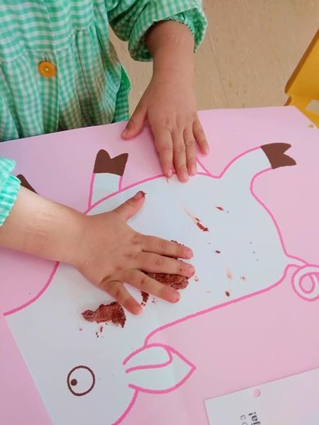Un niño está jugando con una imagen de un cerdo sobre una mesa.