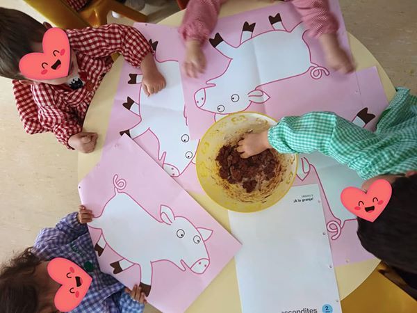Un grupo de niños están sentados alrededor de una mesa con dibujos de cerdos.