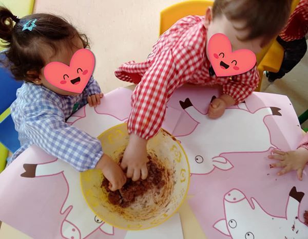 Dos niños con corazones en sus caras están jugando con comida.