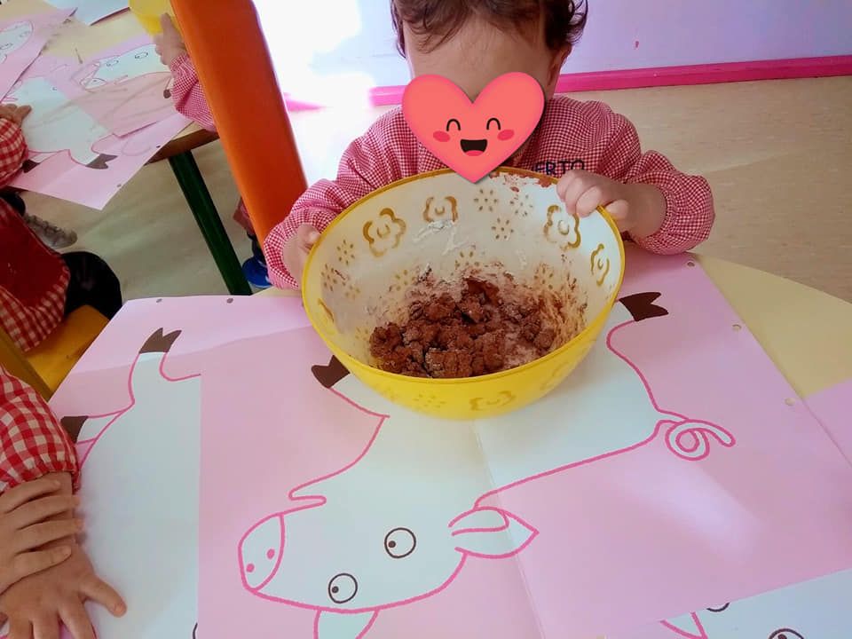 Una niña está sentada en una mesa con un plato de comida.