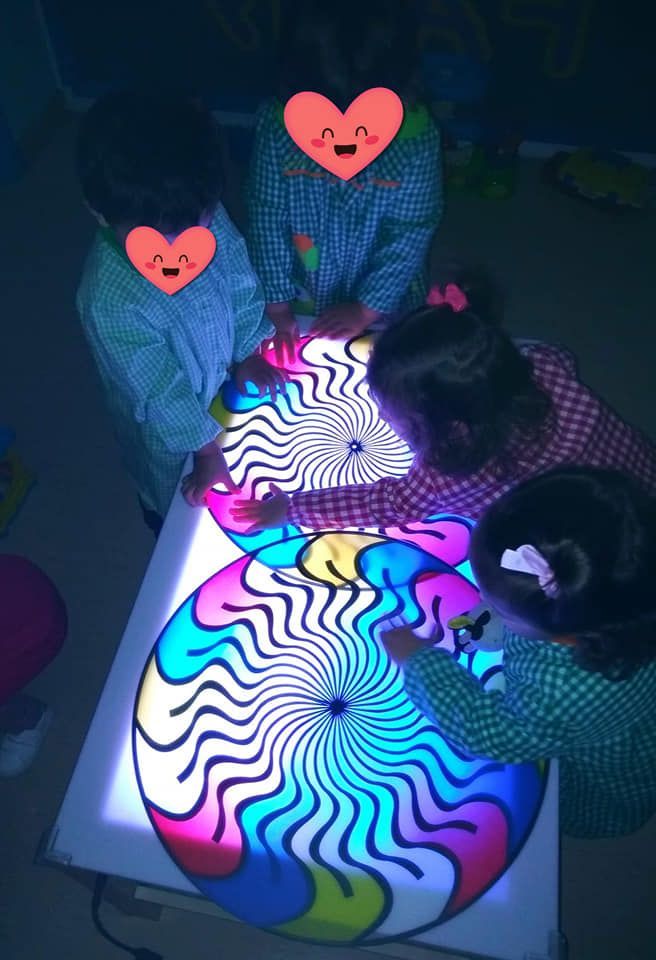 Un grupo de niños está jugando con una caja de luz de colores.