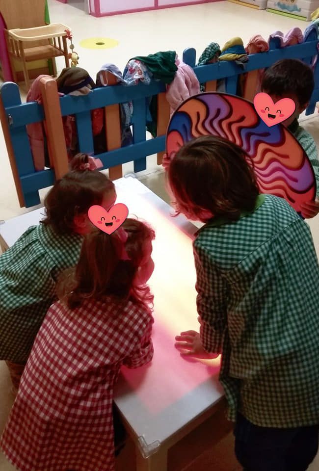 Un grupo de niños están sentados en una mesa con corazones en el pelo.