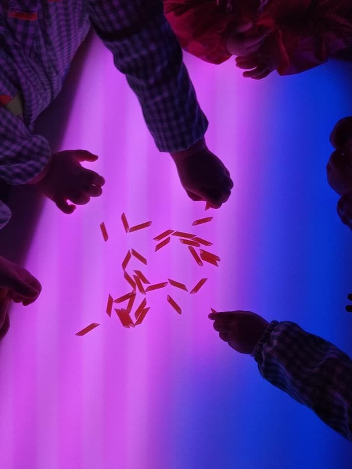 Un grupo de niños juega con luces moradas y azules.