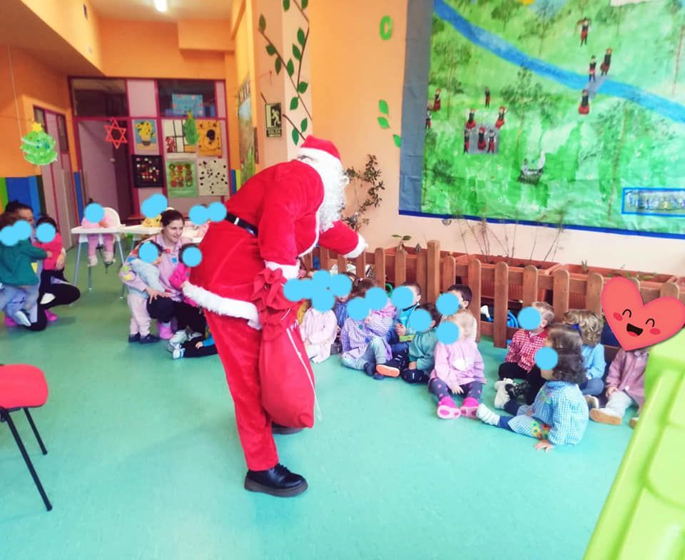 Un hombre vestido como Papá Noel está de pie frente a un grupo de niños.