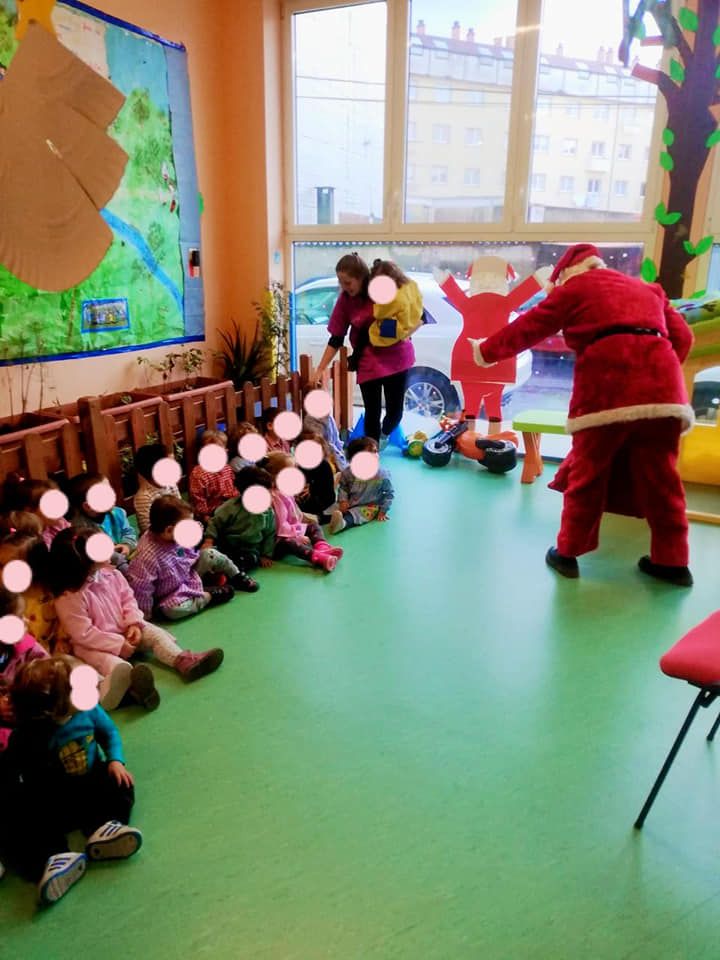 Un grupo de niños están sentados en el suelo mirando a un hombre vestido de Papá Noel.