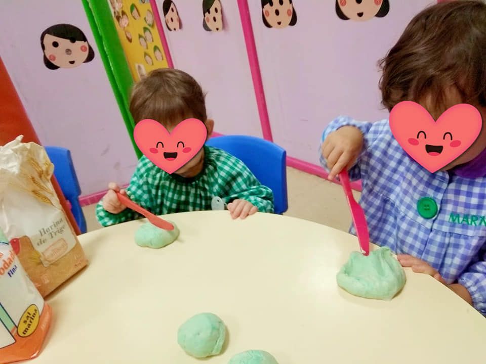 Dos niños con corazones en sus caras están jugando con plastilina.