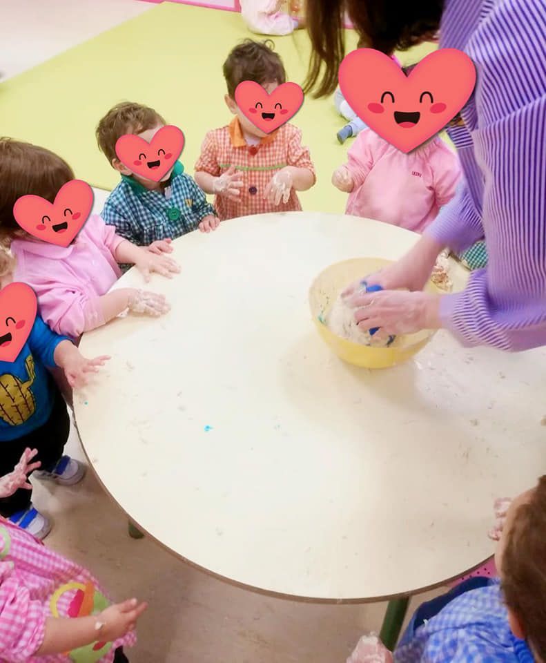 Un grupo de niños sentados alrededor de una mesa con corazones en sus caras.