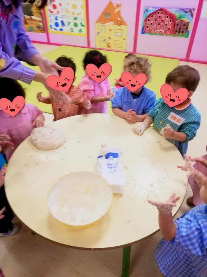Un grupo de niños están sentados alrededor de una mesa con corazones en sus caras.