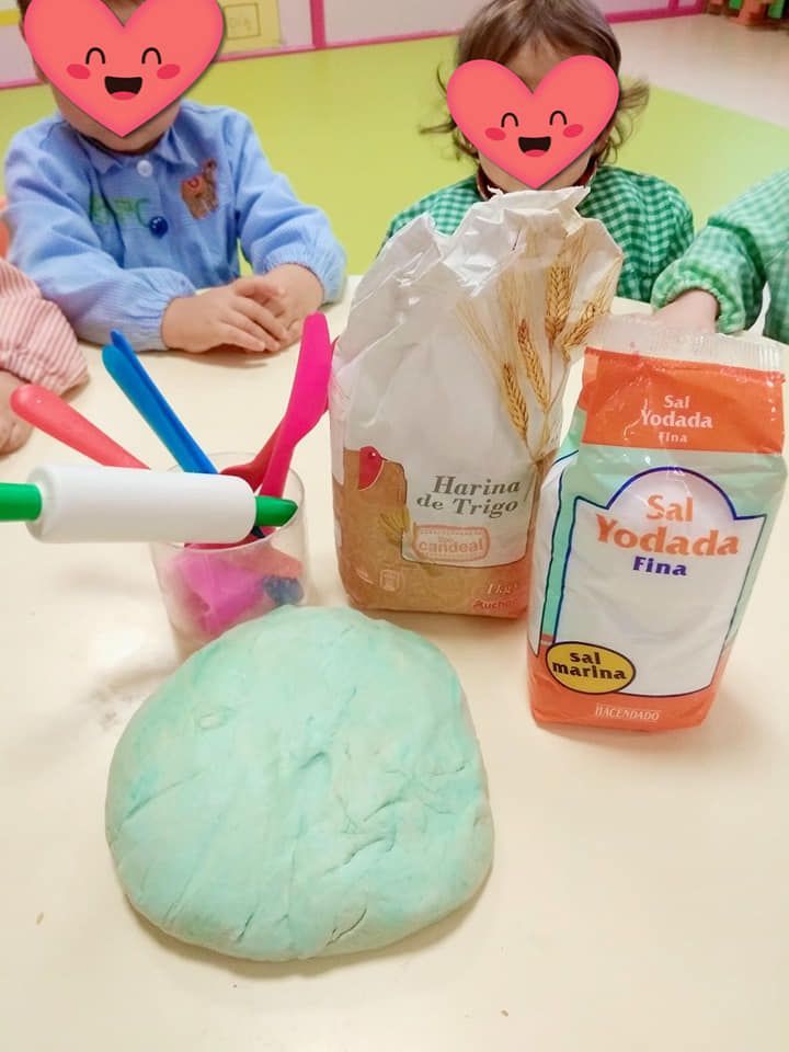 Dos niños están sentados en una mesa con una bolsa de sal yodada.