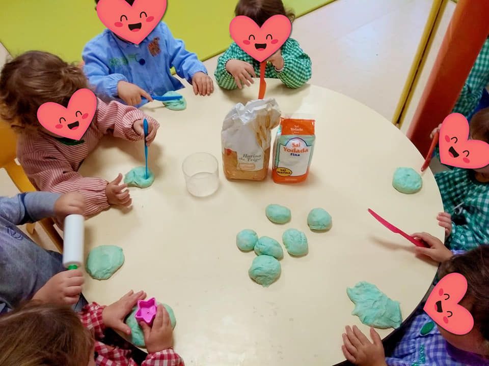Un grupo de niños están sentados alrededor de una mesa jugando con plastilina.