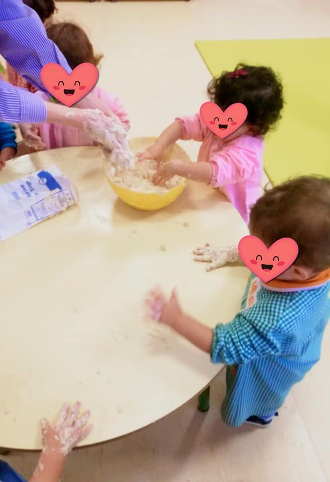 Un grupo de niños está jugando con harina en una mesa.