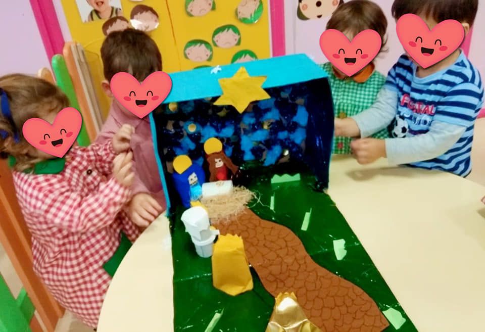 Un grupo de niños juega con un belén hecho de cartón.