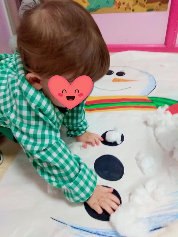 Un bebé con un corazón en la cara está jugando con bolas de algodón.