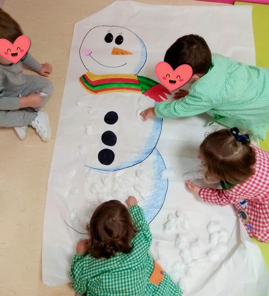 Un grupo de niños está jugando con un muñeco de nieve hecho de nieve.