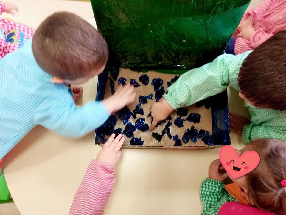 Un grupo de niños está jugando con una caja de arándanos.