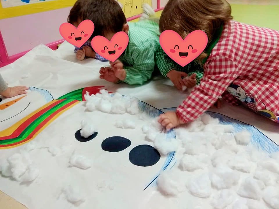 Dos niños están acostados en el suelo jugando con nieve y bolas de algodón.