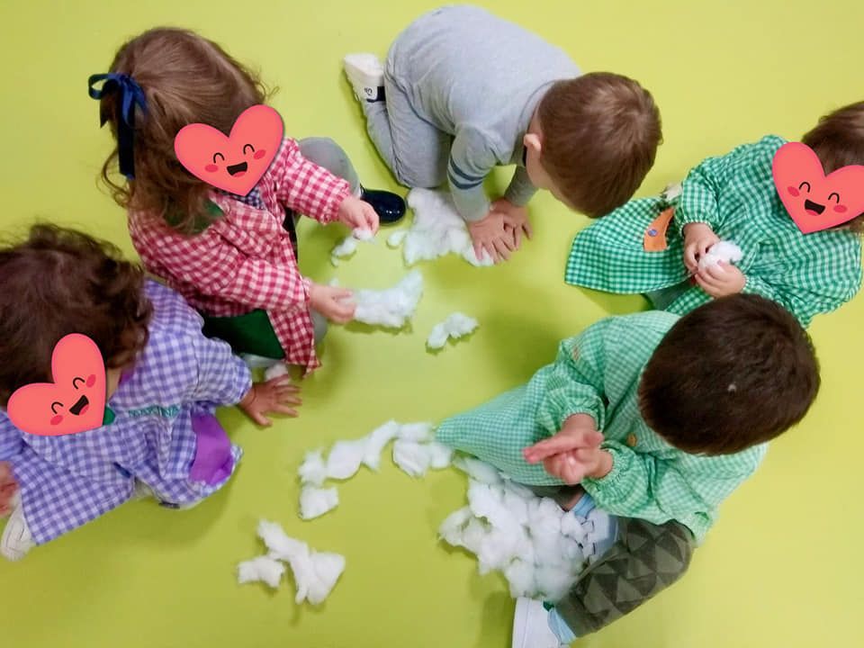 Un grupo de niños está jugando con bolas de algodón en el suelo.
