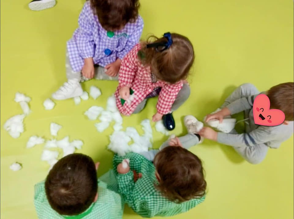 Un grupo de niños están sentados en el suelo jugando con nieve.