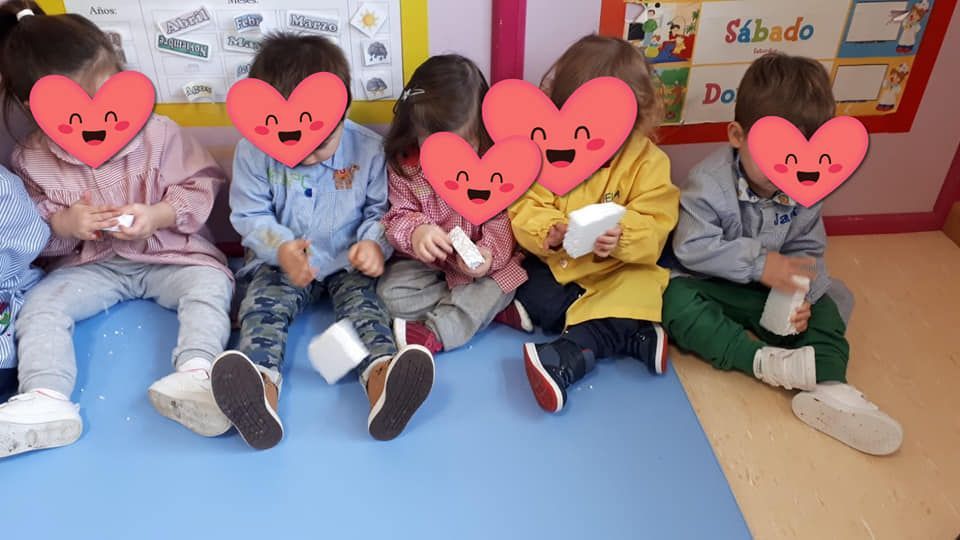 Un grupo de niños están sentados en el suelo con corazones en sus caras.