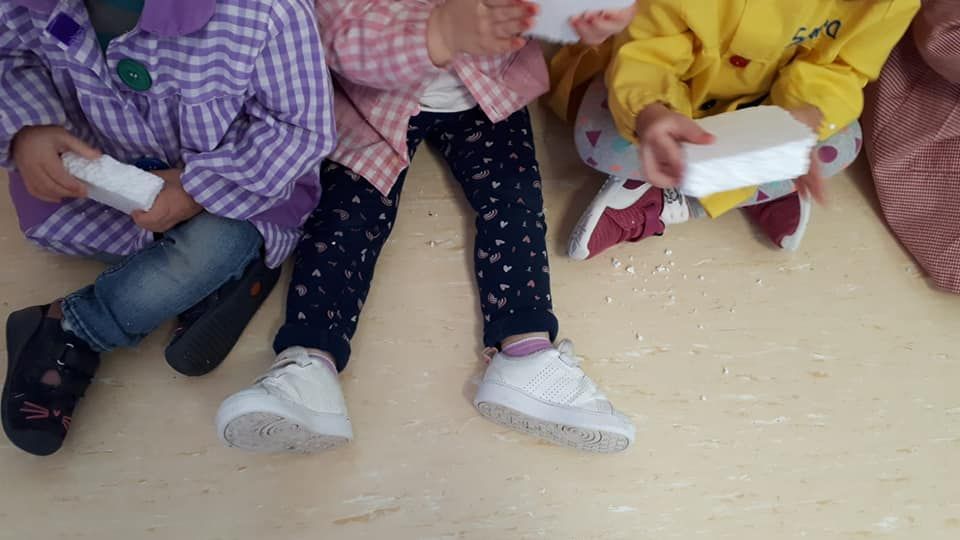 Un grupo de niños está sentado en el suelo sosteniendo cajas.