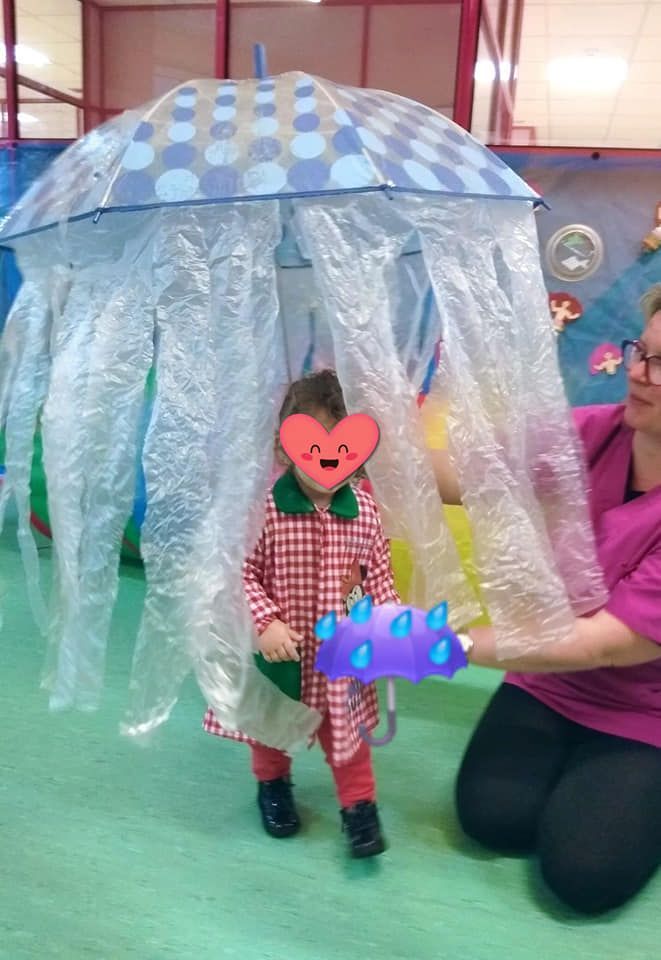 Una mujer está arrodillada junto a un niño vestido de medusa.