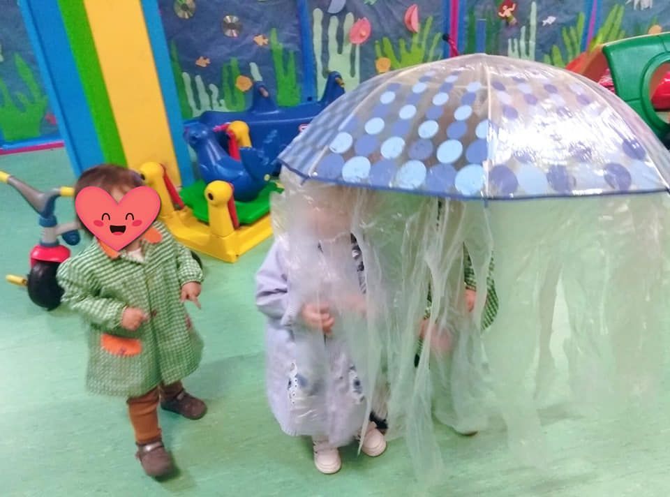 Dos niños están parados bajo un paraguas en una habitación.