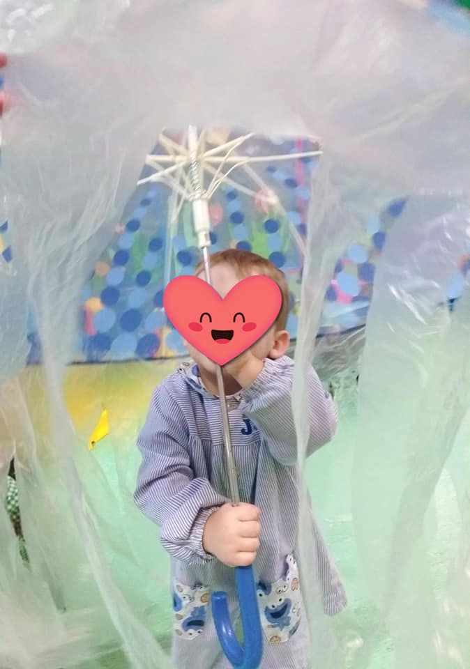 Un niño pequeño sostiene un paraguas frente a su cara.