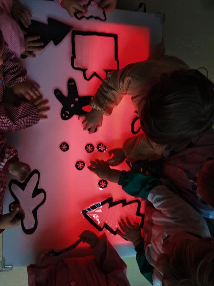 Un grupo de niños está jugando con adornos navideños en una mesa.