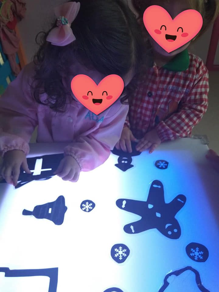 Dos niñas con corazones en sus caras están jugando en una mesa de luz.