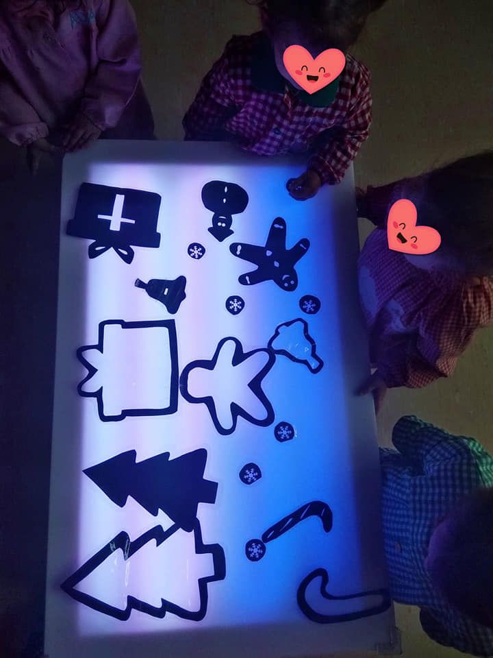 Los niños están jugando con una caja de luz con formas navideñas.
