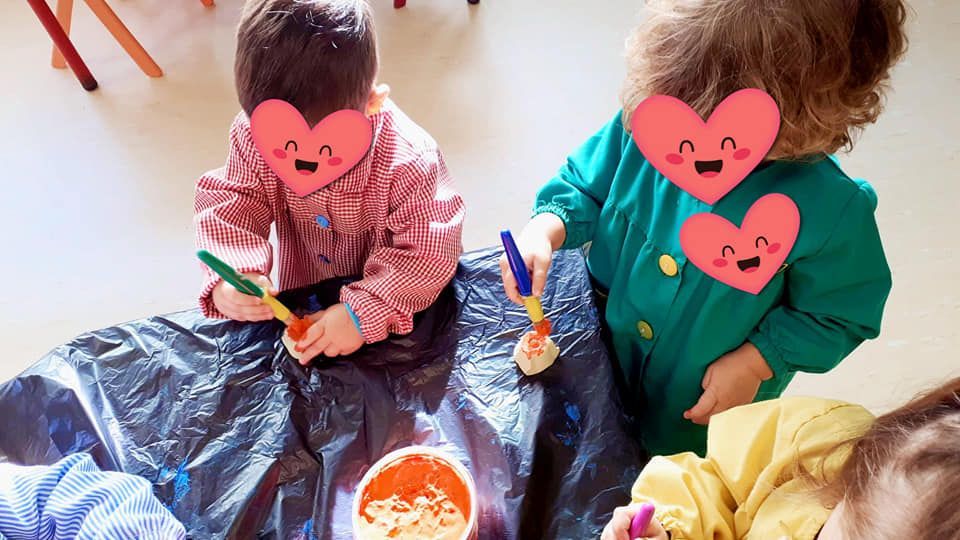 Un grupo de niños está sentado en el suelo jugando con pintura.
