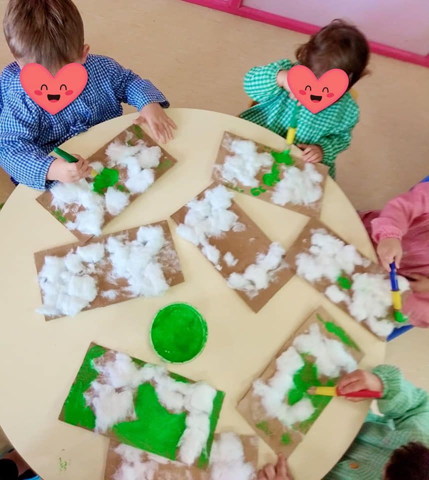 Un grupo de niños están sentados alrededor de una mesa haciendo manualidades.