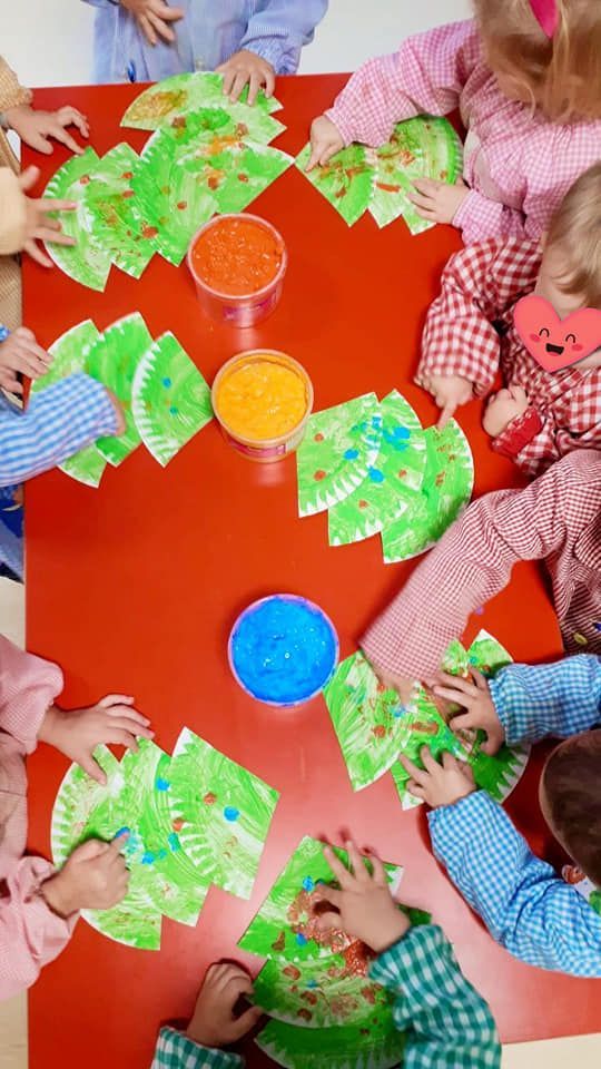 Un grupo de niños están sentados alrededor de una mesa haciendo manualidades.