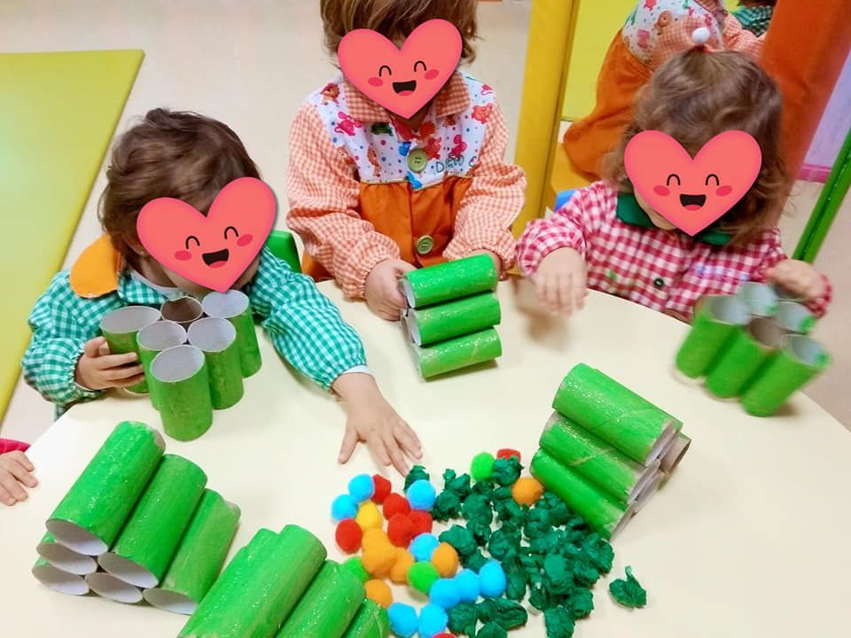 Un grupo de niños con corazones en sus caras están jugando con rollos de papel higiénico verdes.