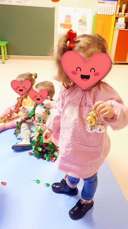 Una niña con un corazón en la cara está parada en una habitación con otros niños.