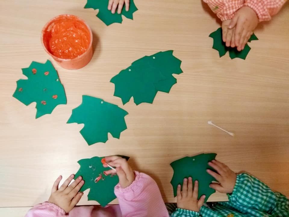 Un grupo de niños está jugando con hojas verdes en una mesa.