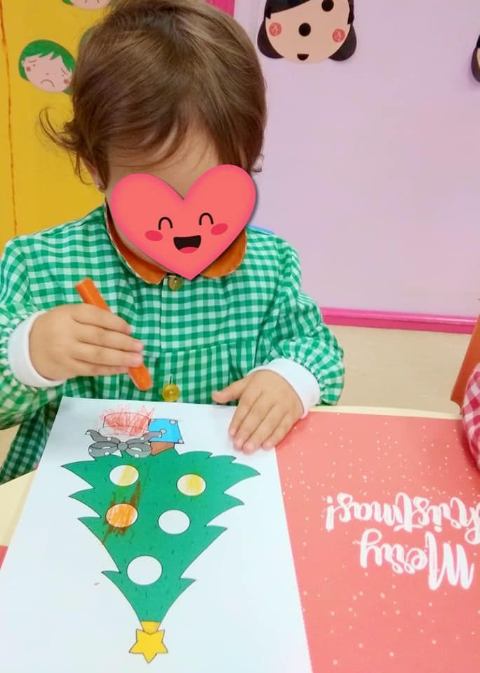 Una niña con un corazón en la cara está dibujando un árbol de Navidad.