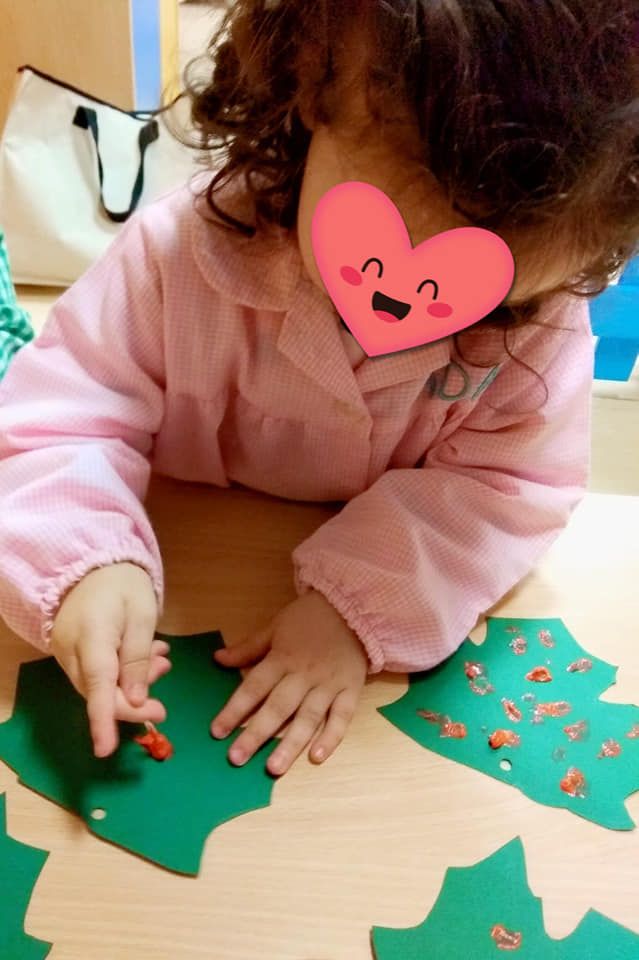 Una niña con un corazón en la cara está haciendo un árbol de Navidad.