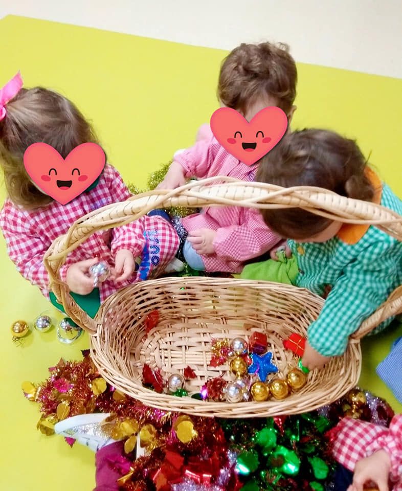 Tres niños con corazones en sus caras están jugando con una canasta de dulces.