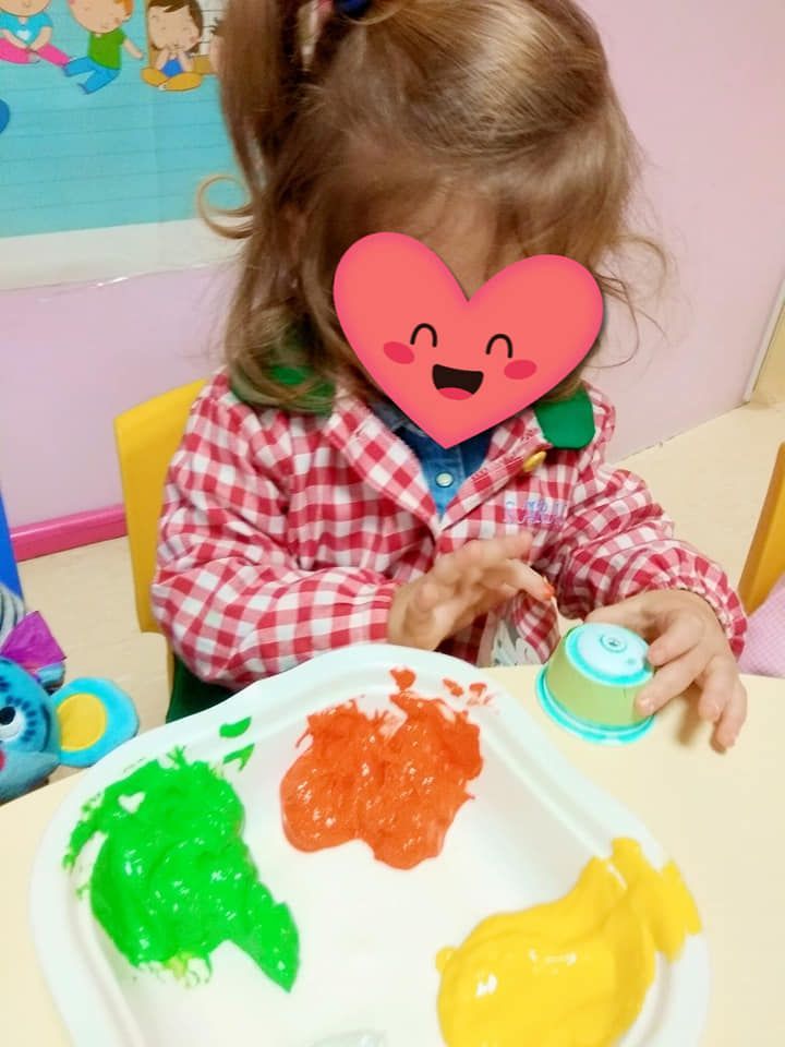 Una niña con un corazón en la cara está jugando con pintura.