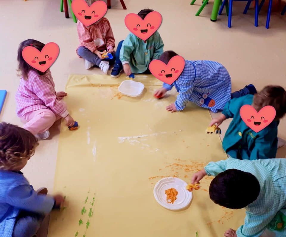 Un grupo de niños sentados en el suelo con corazones en sus caras.
