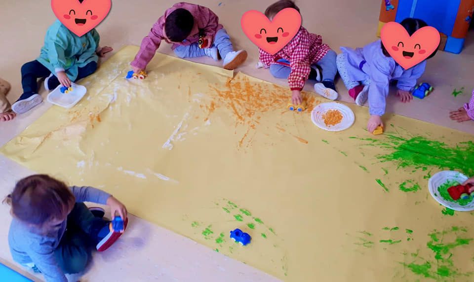 Un grupo de niños está sentado en el suelo jugando con pintura.