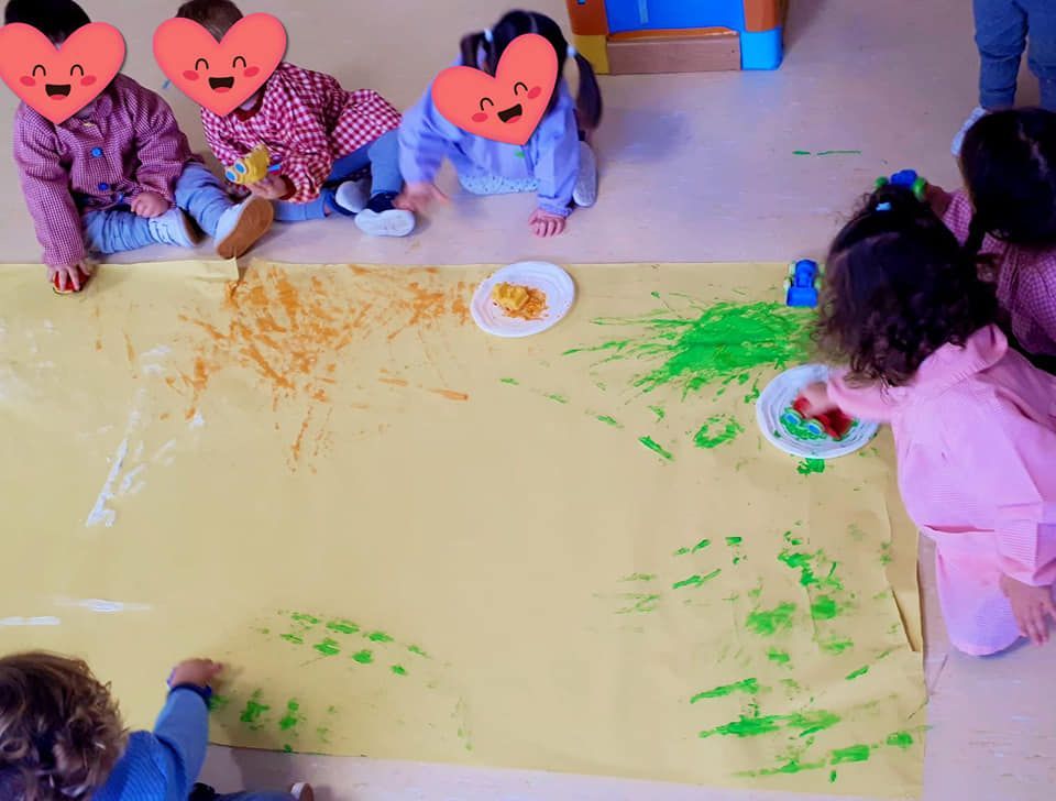 Un grupo de niños están sentados en el suelo jugando con pintura.